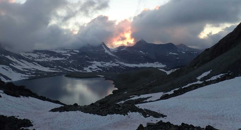 An alpine lake is nestled amongst snow capped mountains of the high sierra 